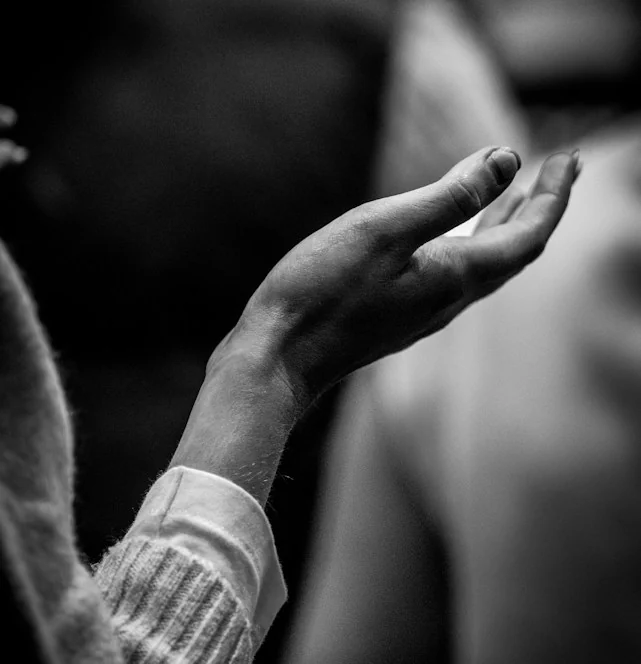 Mãos abertas em oração, numa fotografia a preto e branco